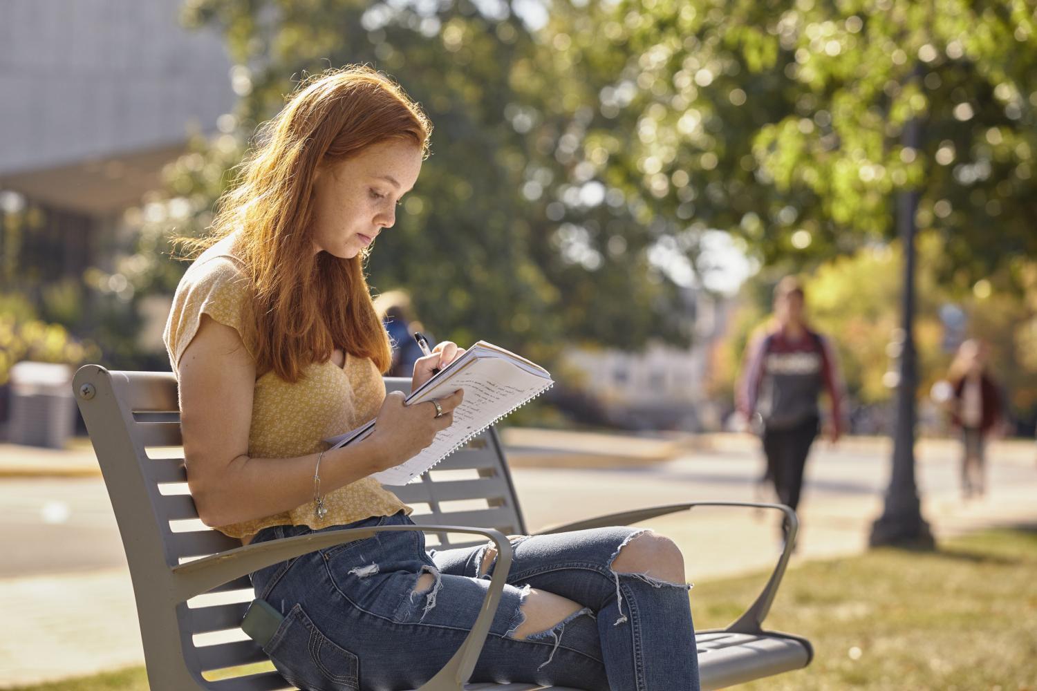 一位<a href='http://7w0r.cq-hw.com'>bv伟德ios下载</a>学院的学生在校园里的长椅上读书.